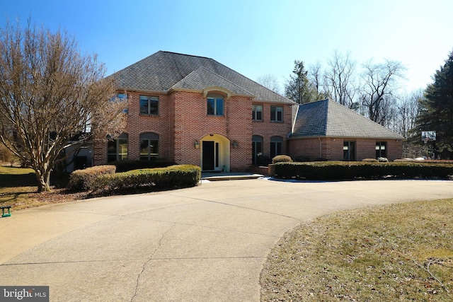 view of front of property featuring driveway, a high end roof, and brick siding