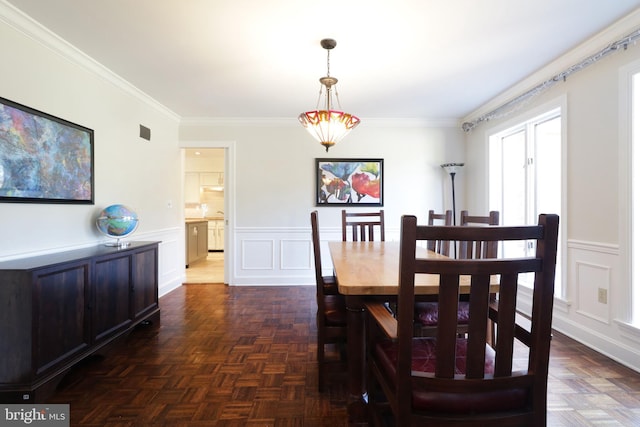 dining space with a wainscoted wall, ornamental molding, and a decorative wall