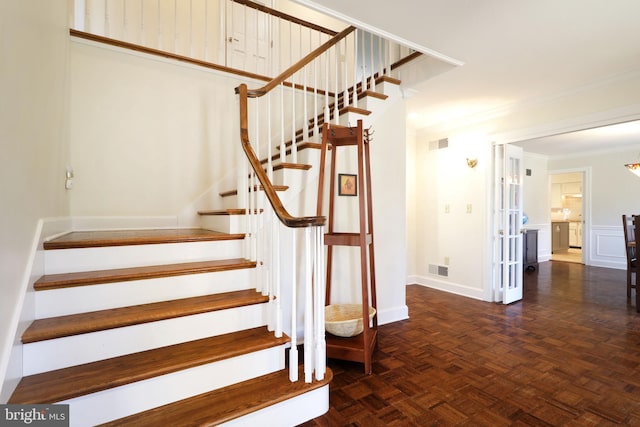 stairway with ornamental molding, visible vents, and baseboards