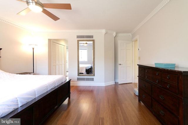 bedroom with dark wood-style floors, baseboards, visible vents, and ornamental molding