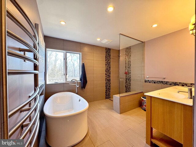 bathroom with visible vents, walk in shower, a freestanding bath, tile walls, and recessed lighting