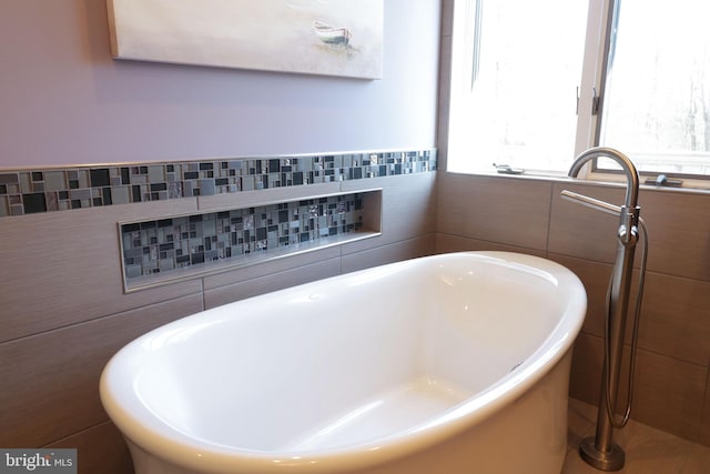 bathroom featuring a freestanding bath and tile walls