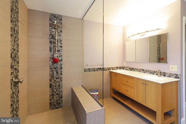 bathroom featuring double vanity, tiled shower, a sink, and tile walls