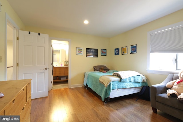 bedroom with light wood-type flooring, ensuite bath, and baseboards