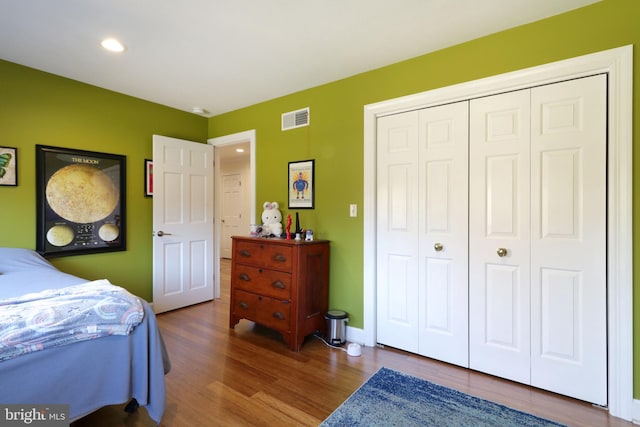 bedroom with recessed lighting, wood finished floors, visible vents, baseboards, and a closet