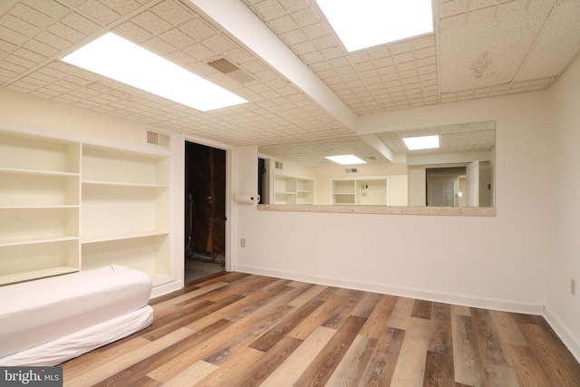 spare room featuring built in features, baseboards, visible vents, and wood finished floors