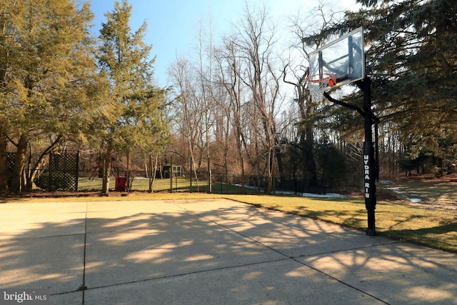 view of basketball court with community basketball court, fence, and a lawn