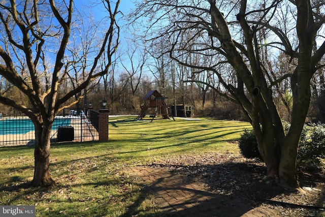 view of yard featuring a fenced in pool, fence, and playground community