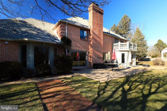 rear view of house featuring a chimney, a lawn, and brick siding