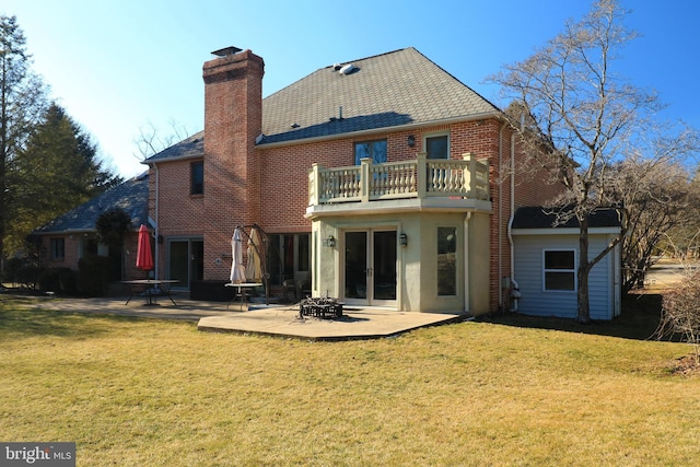 back of house featuring a patio, a balcony, brick siding, a lawn, and a chimney