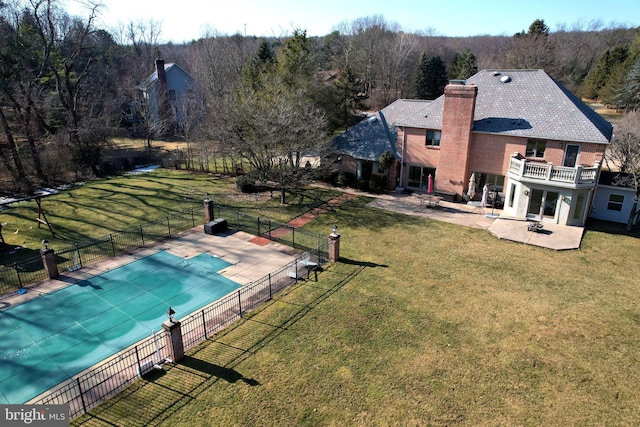 view of pool featuring fence, a lawn, a view of trees, and a patio