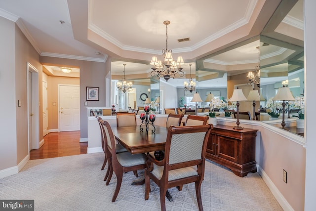 dining area with a chandelier, a tray ceiling, ornamental molding, and visible vents