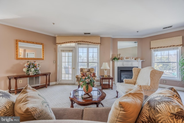 living room with a glass covered fireplace, visible vents, crown molding, and carpet