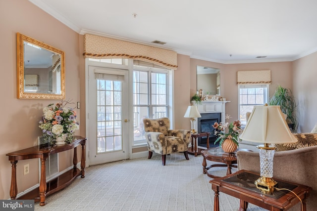 sitting room with carpet, visible vents, crown molding, and a glass covered fireplace