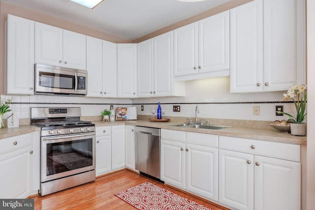 kitchen with appliances with stainless steel finishes, white cabinets, and a sink