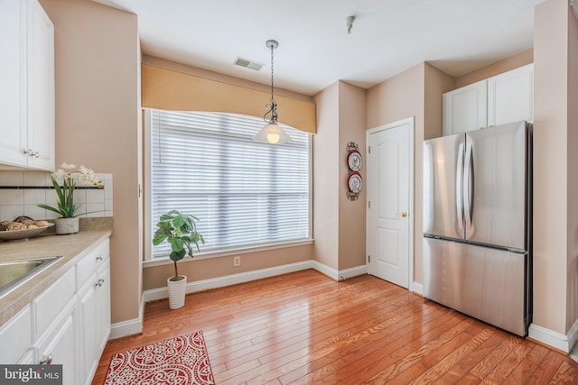 kitchen featuring visible vents, freestanding refrigerator, and white cabinetry