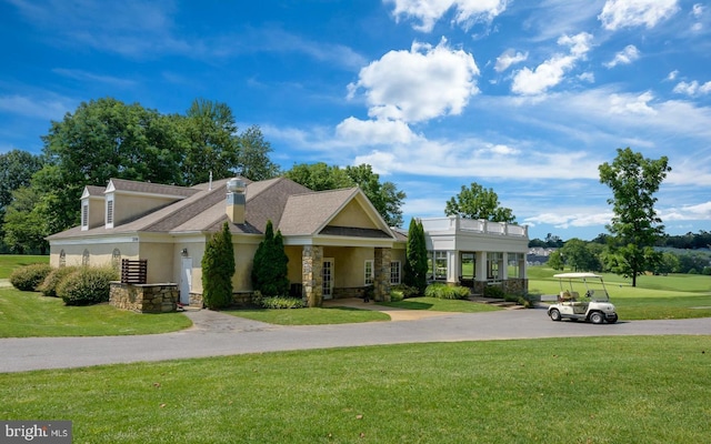 view of front of home with stone siding, a chimney, a front lawn, and stucco siding