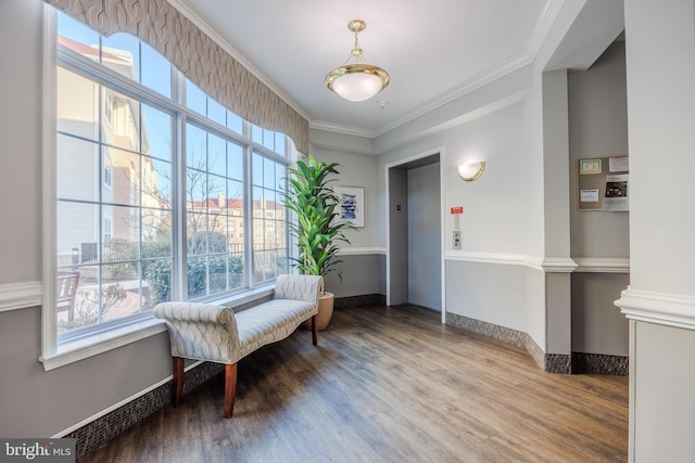 sitting room featuring ornamental molding, elevator, baseboards, and wood finished floors