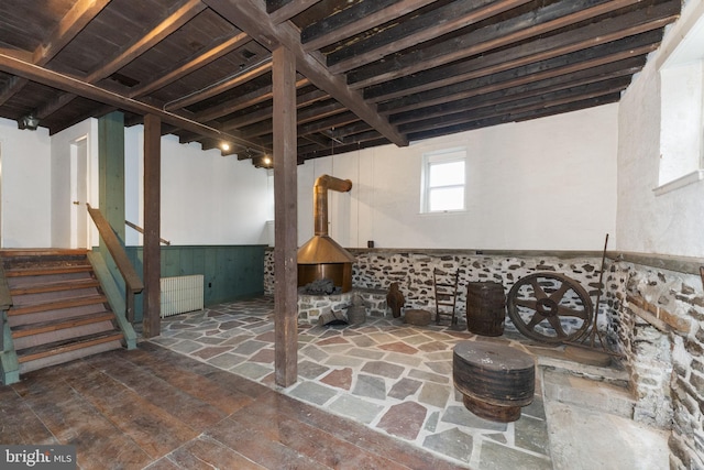 below grade area featuring stone tile floors, wainscoting, and stairs