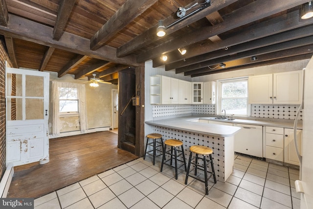 kitchen featuring tasteful backsplash, white cabinetry, a breakfast bar area, light tile patterned floors, and dishwasher