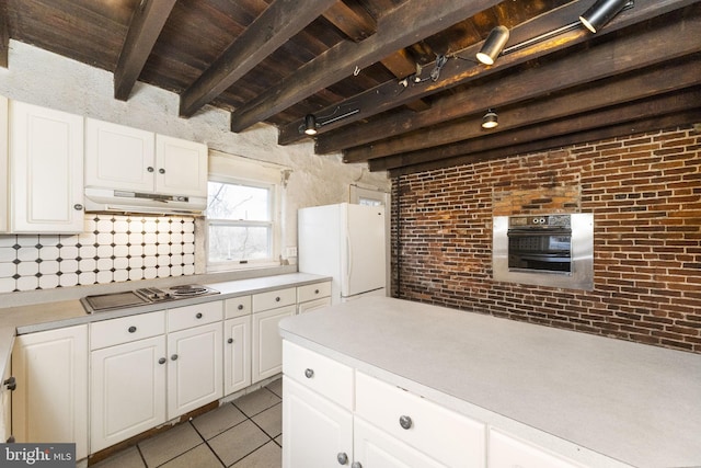 kitchen featuring under cabinet range hood, light countertops, freestanding refrigerator, and oven