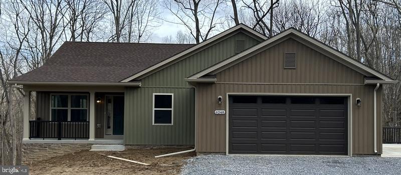 view of front facade featuring a garage, gravel driveway, and roof with shingles