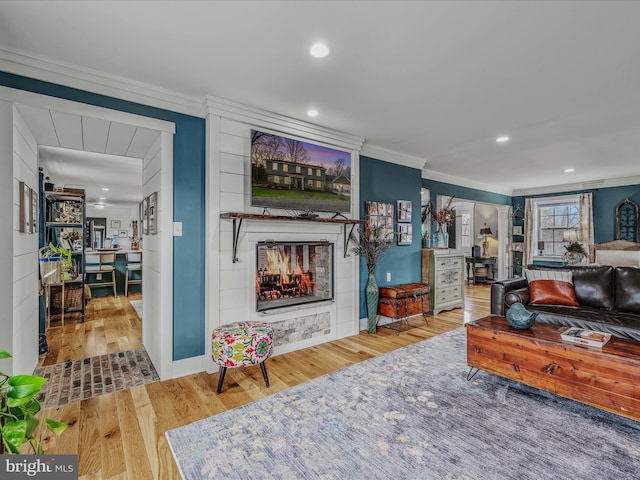 living room featuring ornamental molding, a glass covered fireplace, wood finished floors, and recessed lighting