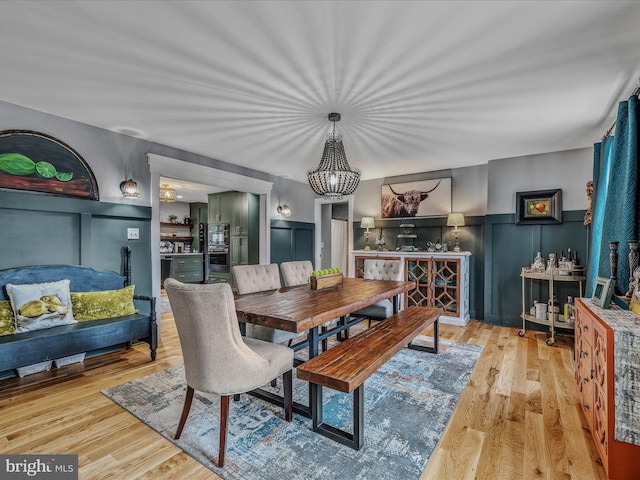 dining area with a wainscoted wall, a decorative wall, and wood finished floors