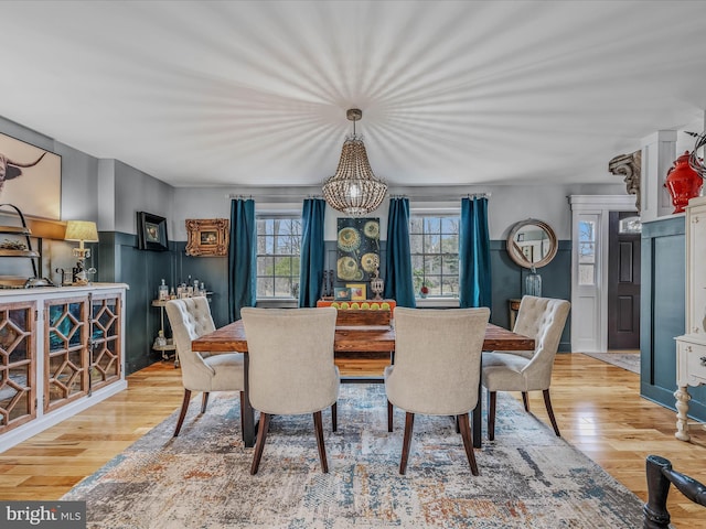 dining space featuring wood finished floors, a wealth of natural light, and wainscoting