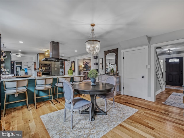 dining space with light wood-type flooring, a notable chandelier, and recessed lighting