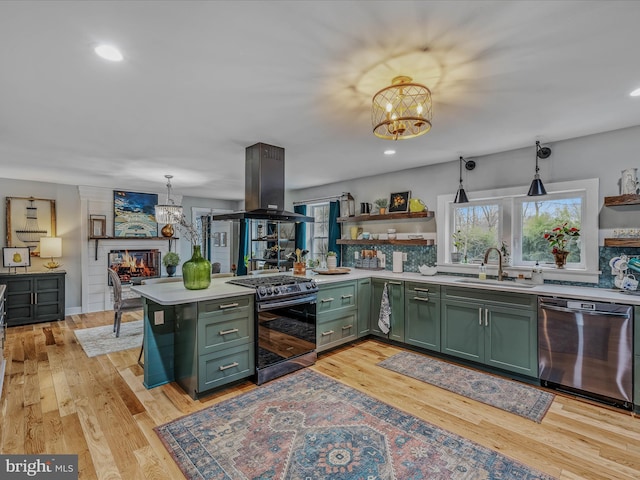 kitchen with a notable chandelier, island exhaust hood, stainless steel appliances, a sink, and green cabinetry