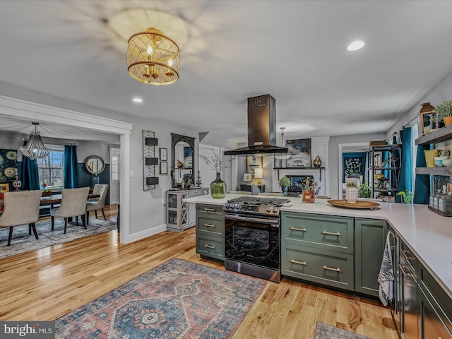 kitchen featuring stainless steel gas stove, island exhaust hood, green cabinets, and light countertops