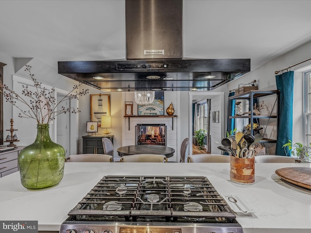 kitchen with island range hood, stove, open floor plan, light countertops, and a multi sided fireplace