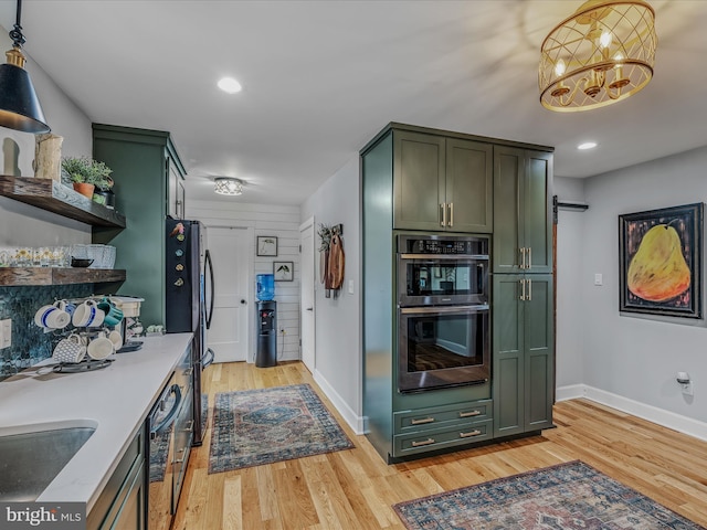 kitchen with light wood-style floors, a barn door, green cabinets, and stainless steel double oven