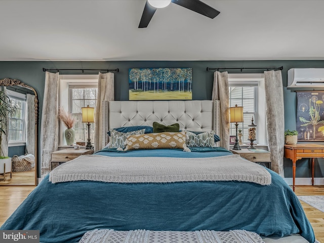 bedroom with ceiling fan, a wall mounted air conditioner, and wood finished floors