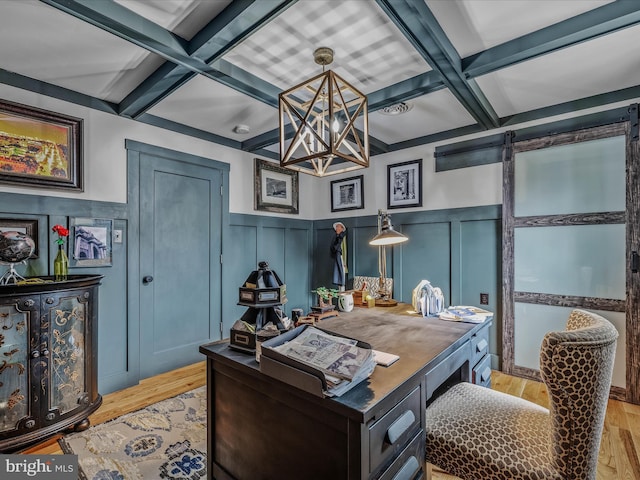 home office featuring light wood-style floors, beam ceiling, coffered ceiling, and a barn door