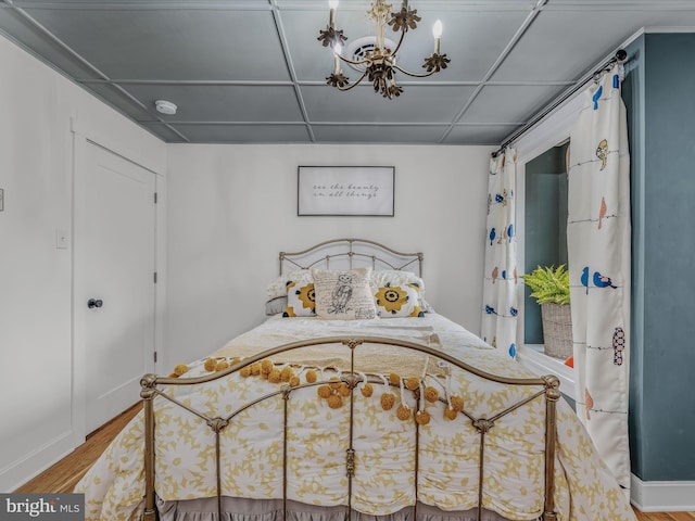 bedroom with a chandelier, a drop ceiling, and wood finished floors