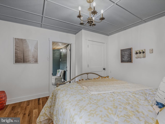 bedroom featuring baseboards, a chandelier, and wood finished floors