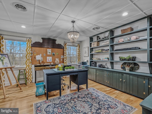 home office with light wood finished floors, visible vents, a drop ceiling, and an inviting chandelier