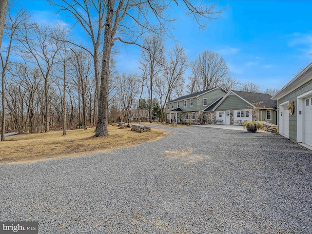 view of side of property with gravel driveway, stone siding, and a garage