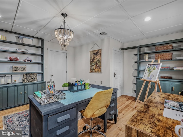 office space with light wood-style flooring, visible vents, a chandelier, and a drop ceiling