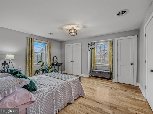 bedroom with light wood-style flooring, a closet, visible vents, and baseboards