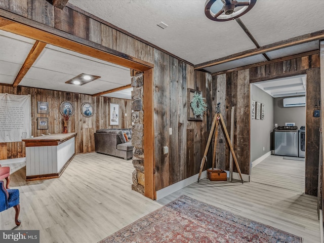 interior space with separate washer and dryer, a wall mounted AC, light wood-style flooring, and wooden walls