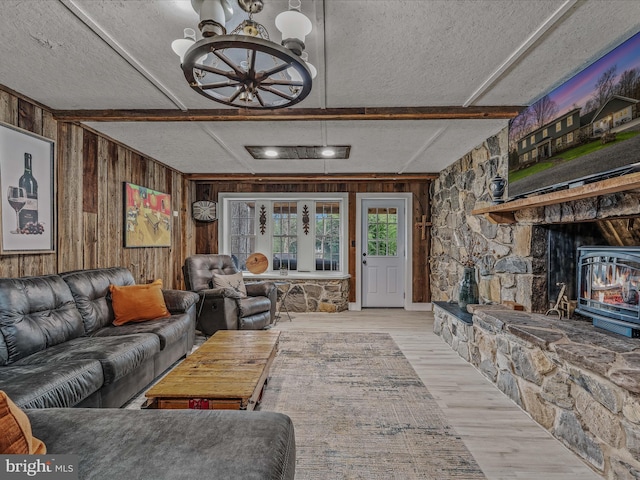 living area with beamed ceiling, wood walls, wood finished floors, and a wood stove