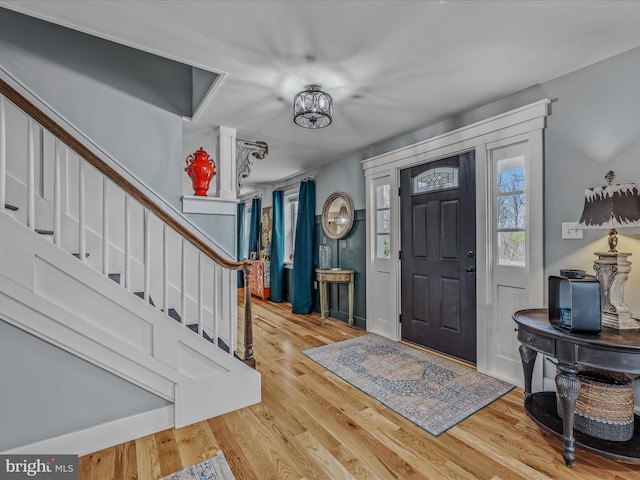 entryway with stairway, wood finished floors, and a notable chandelier