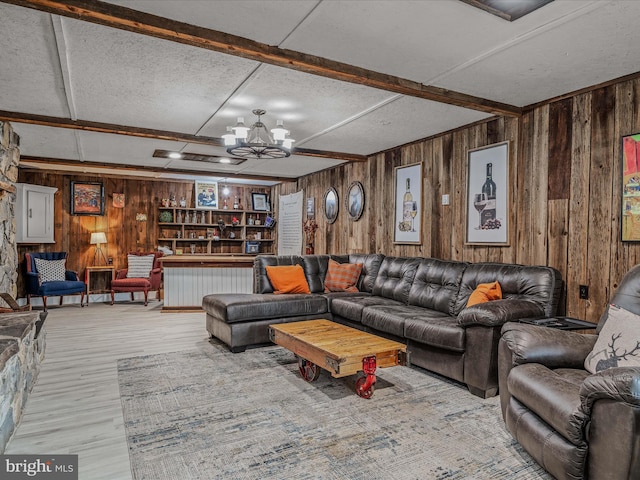 living area featuring wooden walls, beamed ceiling, and a notable chandelier