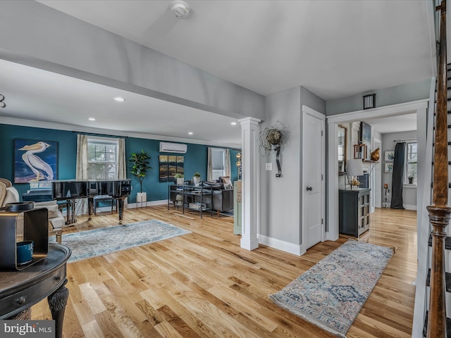 entrance foyer featuring baseboards, an AC wall unit, light wood finished floors, and ornate columns