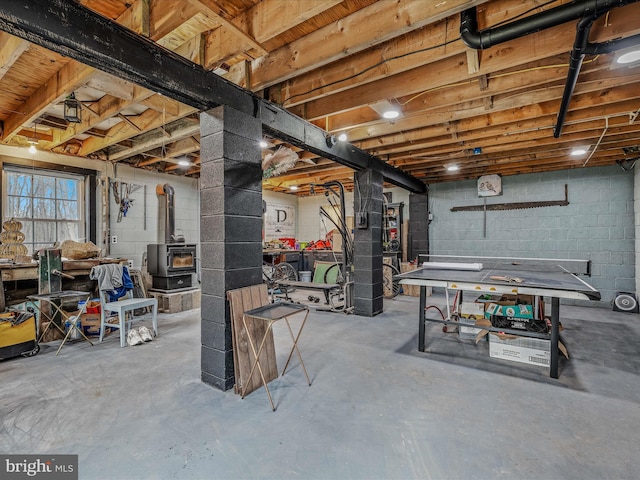 below grade area featuring a wood stove and concrete block wall