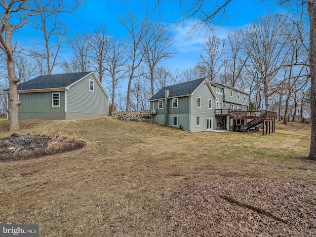 view of side of home with a shingled roof, a lawn, stairway, and a wooden deck