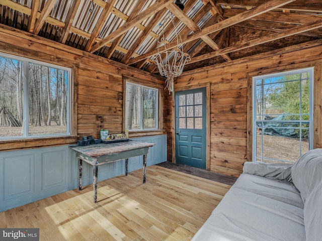 interior space with an inviting chandelier, light wood-style flooring, vaulted ceiling, and a wealth of natural light